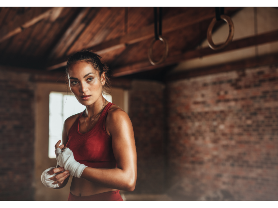Femme en tenue de sport préparant ses mains avant l'entraînement, symbolisant la préparation et la protection contre les manipulateurs.